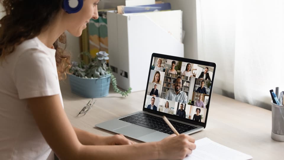 Kvinna med mörkt hår sitter framför en dator i ett digitalt möte.