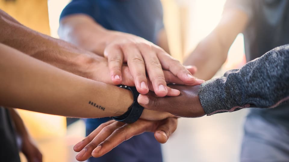 Office employee group with hands in to show collaboration, trust and motivation for corporate job success.